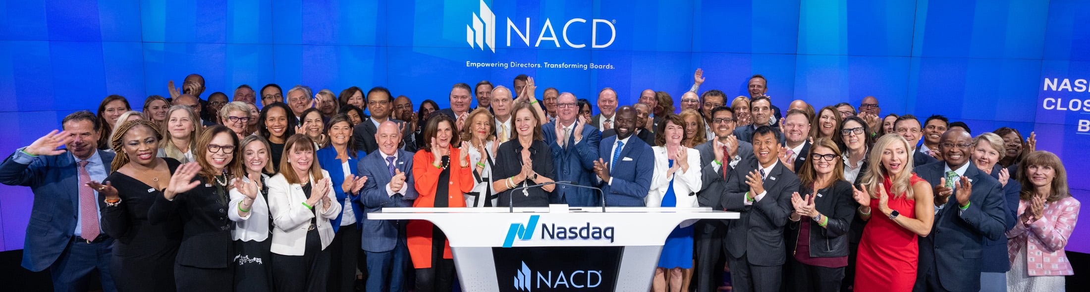  NACD company employees standing in front of a podium at the NASDAQ exchange